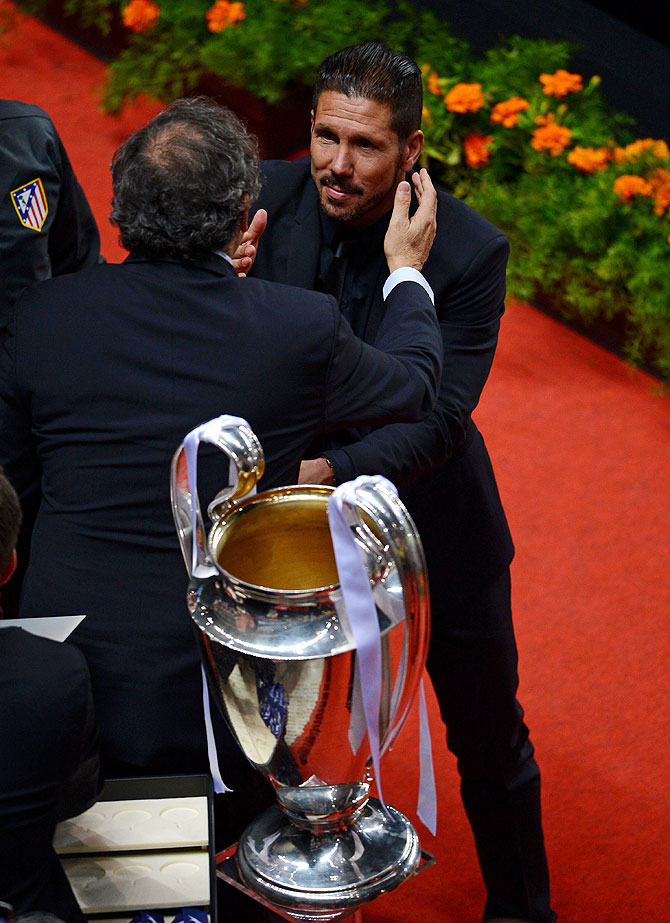 UEFA President Michel Platini presents Diego Simeone, coach of Club Atletico de Madrid with his runners up medal after the UEFA Champions League final on Saturday
