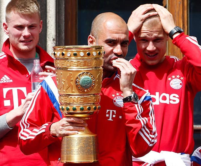 Bayern Munich's coach Pep Guardiola holds the German Cup trophy
