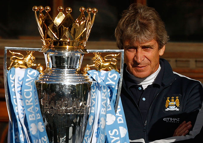 Manchester City's manager Manuel Pellegrini looks at the English Premier League trophy
