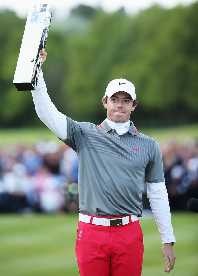 Rory McIlroy of Northern Ireland celebrates victory as he poses with the trophy