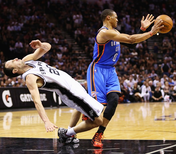 Manu Ginobili of the San Antonio Spurs falls to the court after colliding   with Russell Westbrook of the Oklahoma City Thunder