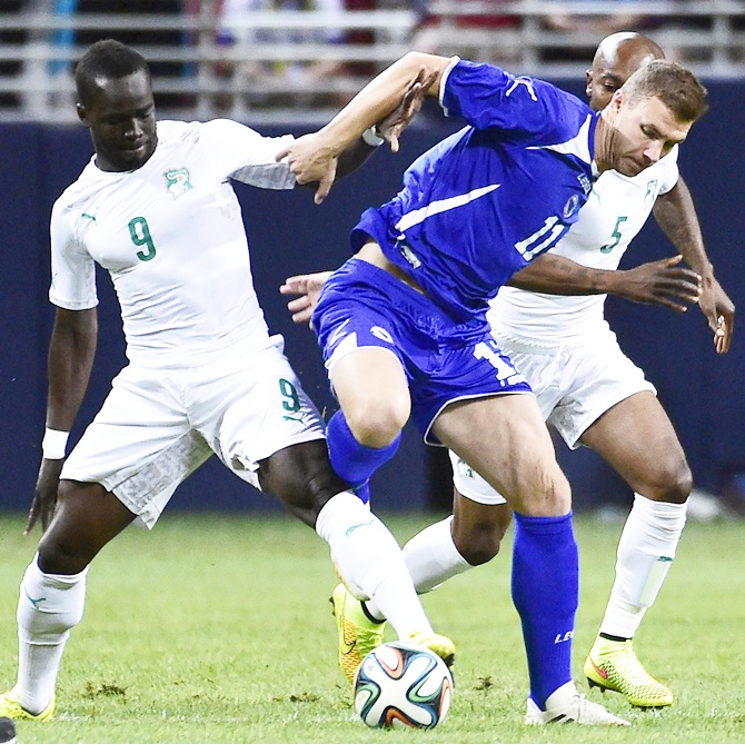 Bosnia player Edin Dzeko, centre, battles for the ball between Ivory Coast players Ismael Tiote Cheik and Didier Zokora