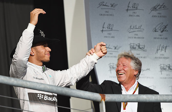 Lewis Hamilton of Great Britain and Mercedes GP celebrates on the podium with former champion Mario Andretti following his victory on Sunday