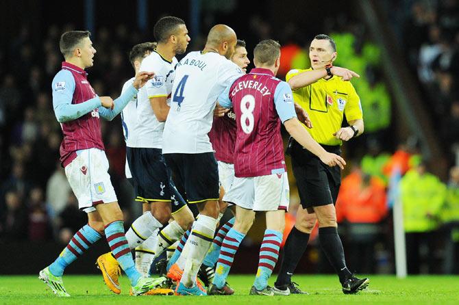 Players from both teams confront referee Neil Swarbrick over a decision