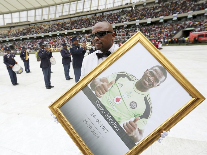A man holds a framed picture of South African national   soccer team goalkeeper and captain, Senzo Meyiwa