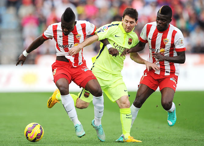 Thievy Guivane (left) and Thomas Partey of Almeria steal possession from Lionel Messi of Barcelona during their La Liga match on Saturday