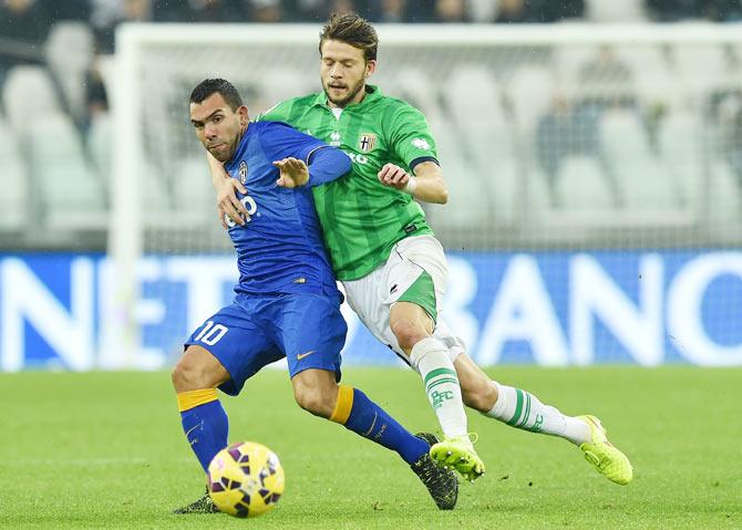 Carlos Tevez (left) of Juventus FC is challenged by Andrea Costa of Parma FC during their Serie A match at Juventus Arena in Turin on Sunday