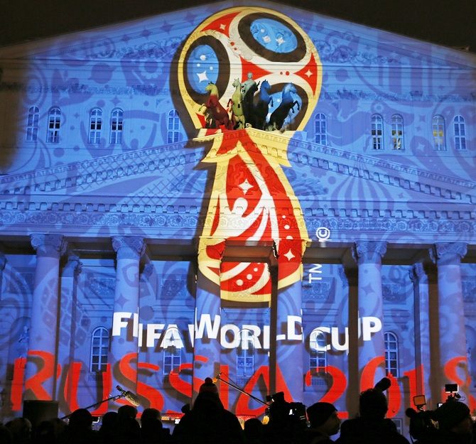 Journalists look at a light installation showing the   official logotype of the 2018 FIFA World Cup