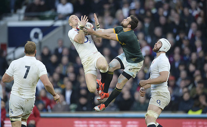 England's Mike Brown (2nd from left) catches the ball despite the attentions of South Africa's Cobus Reinach during their international rugby union match at Twickenham in London on November 15