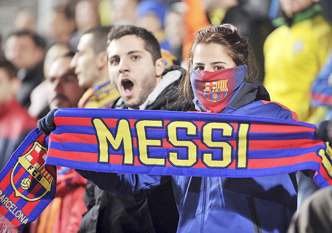 A Barcelona fan holds a scarf with Lionel Messi's name on it during the Champions League Group F soccer match between APOEL Nicosia and Barcelona on Tuesday