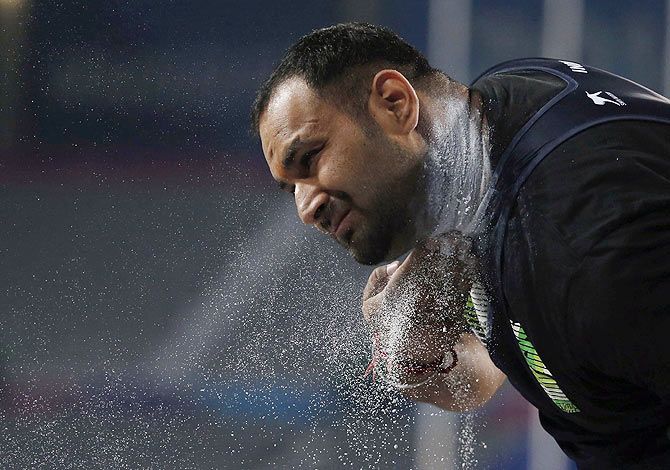 India's Inderjeet Singh chalks his neck as he competes in the men's shot put final at the Incheon Asiad Main Stadium