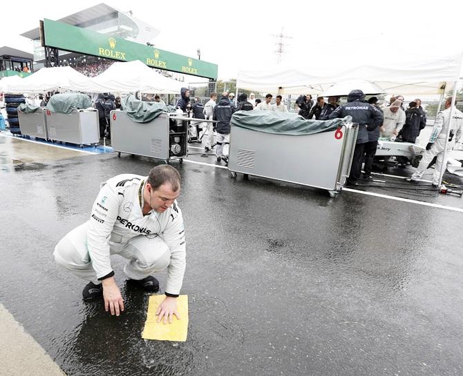 A Mercedes crew member wipes a puddle with a towel