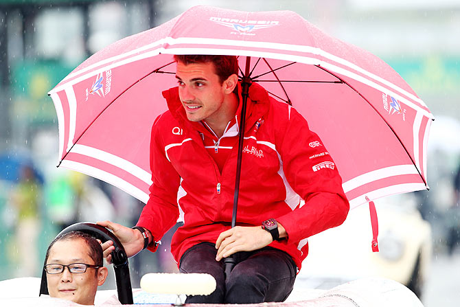 Jules Bianchi of France and Marussia shelters from the rain during drivers parade prior to the Japanese Formula One Grand Prix at Suzuka Circuit on Sunday