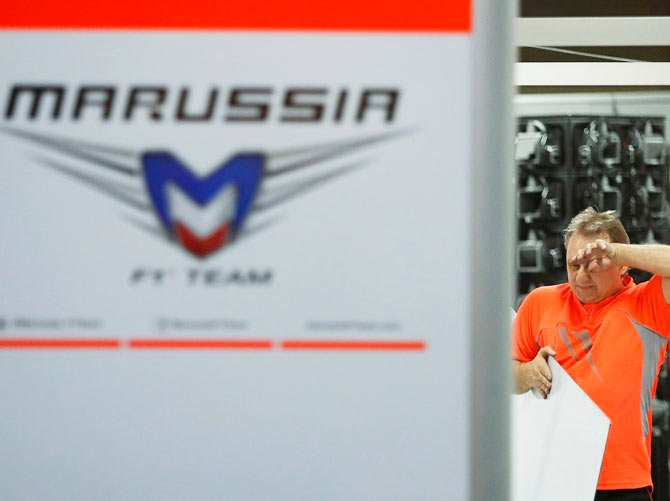 A pit crew of Marussia, which Formula One driver Jules Bianchi of France belongs to, wipes his face as he cleans up the pit after the Japanese F1 Grand Prix