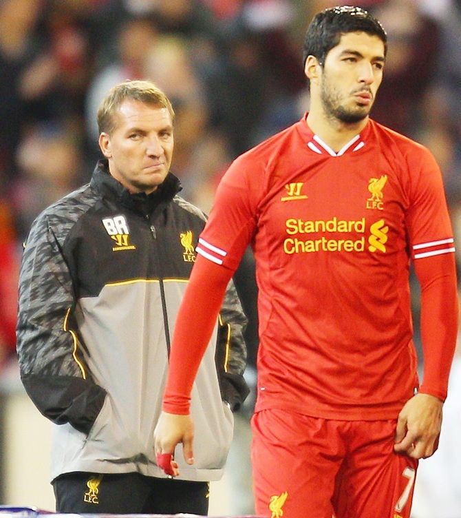 Brendan Rodgers, looks on as Luis Suarez walks away