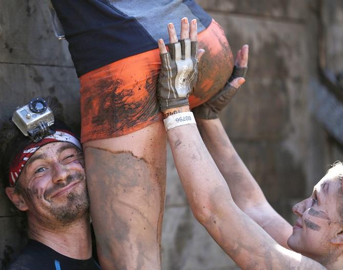 Participants climb over a wall 