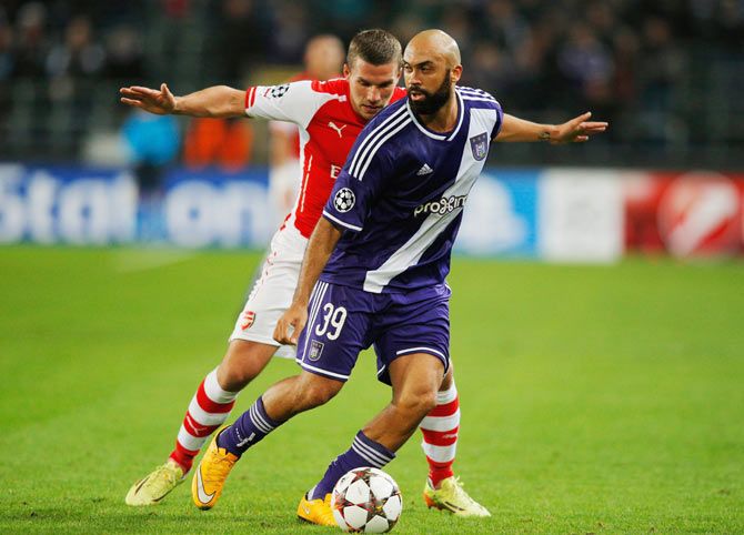 Anthony Vanden Borre of Anderlecht holds off Lukas Podolski of Arsenal during their match on Wednesday