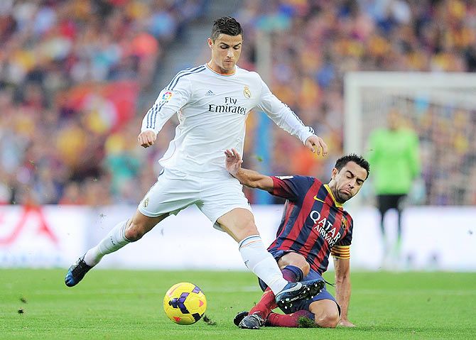 Cristiano Ronaldo of Real Madrid CF (L) is tackled by Xavi Hernandez of FC Barcelona