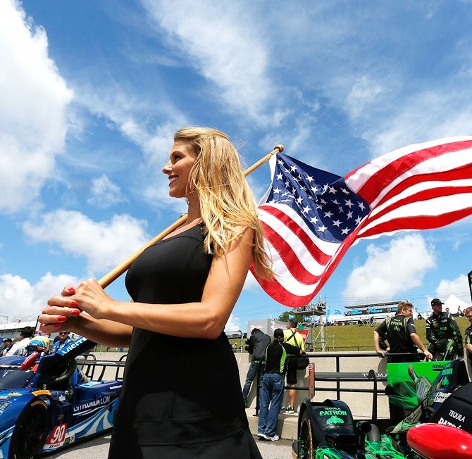 A grid girl holds an American flag