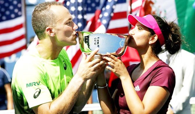 Sania Mirza (right) and Bruno Soares kiss the US Open mixed doubles trophy