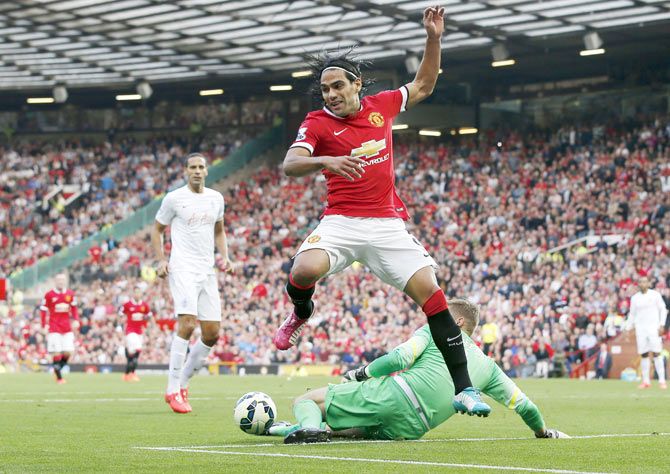 Manchester United's Radamel Falcao (front) is challenged by Queens Park Rangers' goalkeeper Robert Green (right) during their English Premier League soccer match at Old Trafford on Sunday
