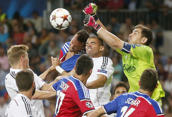 Real Madrid's goalkeeper Iker Casillas (right) and his teammate Pepe fight for the ball with FC Basel's Marco Streller