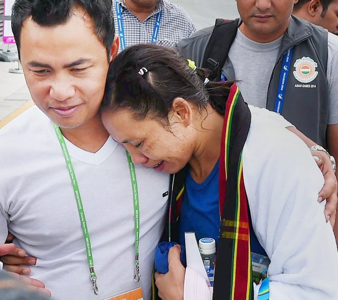 Sarita Devi, right, of India is consoled by her husband
