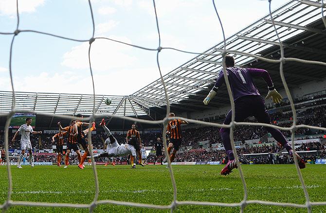 Bafetimbi Gomis of Swansea City scores his team's second goal past Hull City's keeper Allan McGregor during their Premier League match at Liberty Stadium in Swansea, Wales, on Saturday