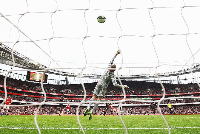 Liverpool keeper Simon Mignolet jumps in vain as Arsenal's Alexis Sanchez scores his team's third goal during their Barclays Premier League match at Emirates Stadium on Saturday