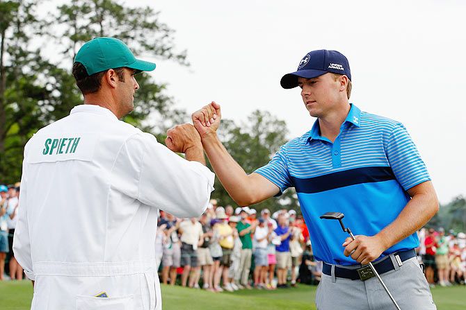 Jordan Spieth of the United States celebrates with his caddie Michael Greller on the 18th green after an eighth-under par 64 during the first round of the 2015 Masters Tournament at Augusta National Golf Club in Augusta, Georgia, on Thursday