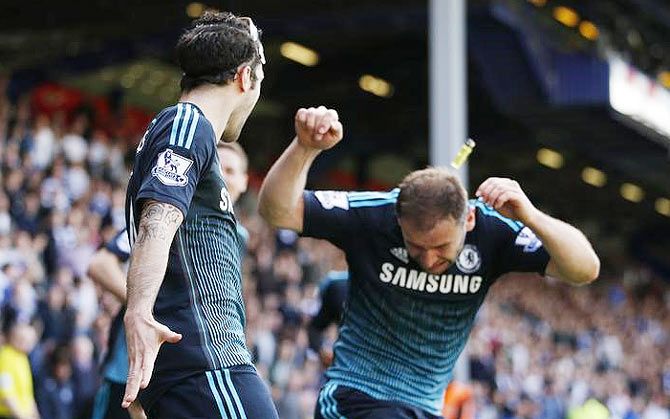 Cesc Fabregas celebrates scoring the first goal for Chelsea as Branislav Ivanovic is hit by lighter thrown from the crowd during their Premier League match on Sunday