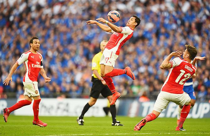 Arsenal's Alexis Sanchez controls the ball as teammates Santi Cazorla (left) and Olivier Giroud (right) watch