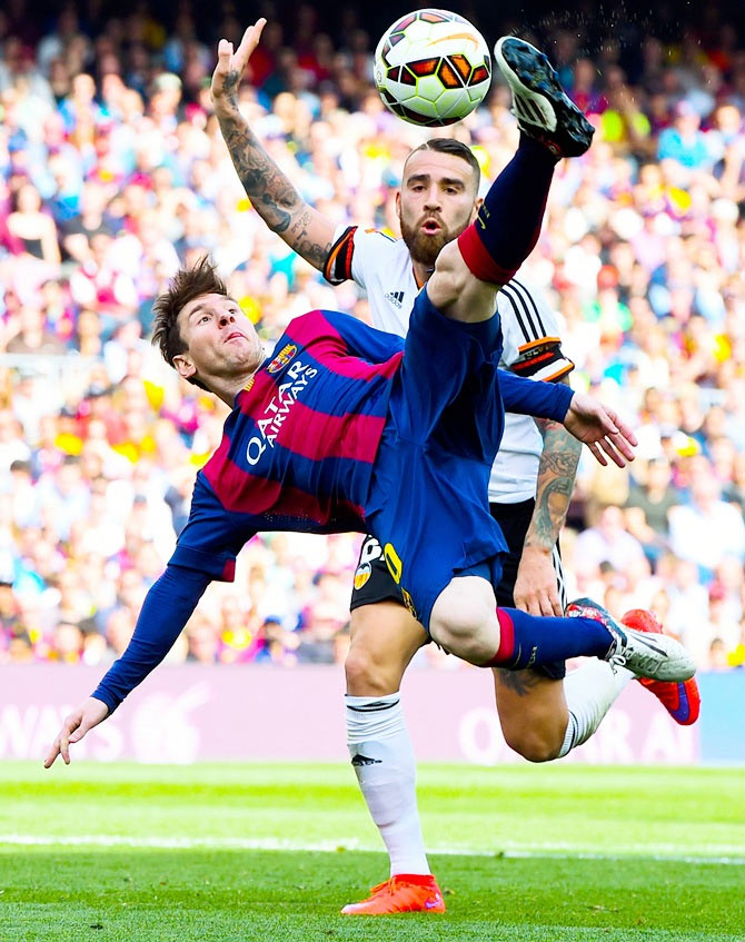 Lionel Messi of FC Barcelona performs an overhead kick under a challenge by Nicolas Otamendi of Valencia