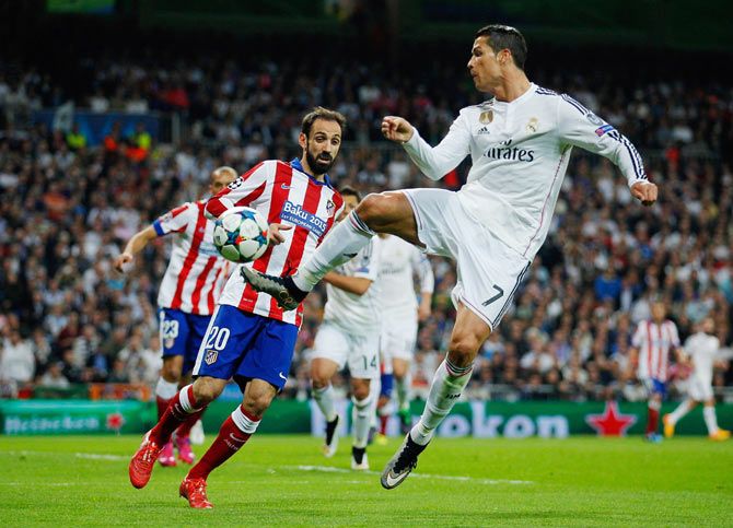Real Madrid's Cristiano Ronaldo is challenged by Atletico's Juanfran