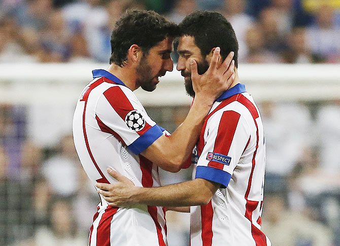 Atletico Madrid's Arda Turan (right) is consoled by teammate Raul Garcia after being sent off during their UEFA Champions League quarter-final second leg match against Real Madrid at the Estadio Santiago Bernabeu on Wednesday
