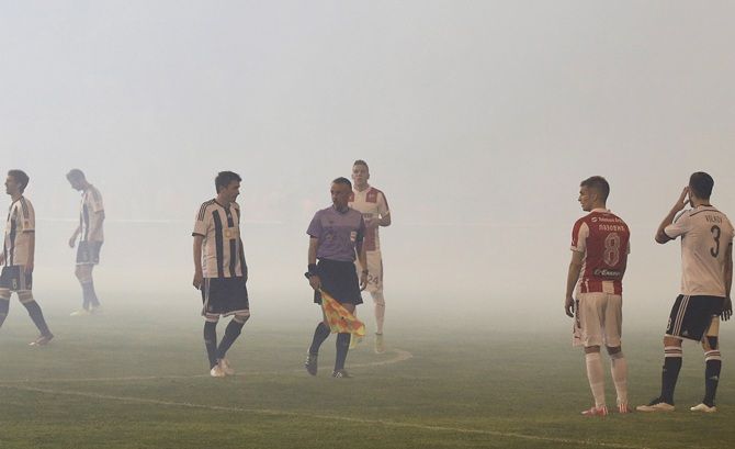 Red Star Belgrade and Partizan Belgrade players stand on the pitch amidst smoke
