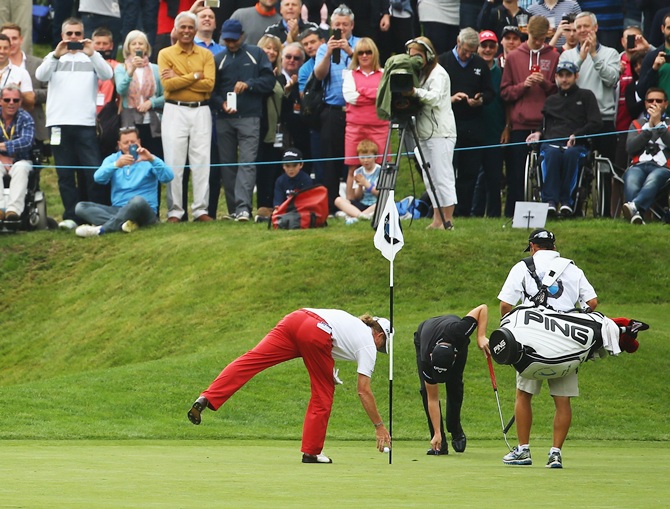 Miguel Angel Jimenez of Spain retrieves his ball after his hole-in-one 