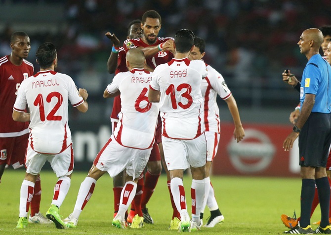 Referee Rajindraparsad Seechurn, right, looks on as players of Tunisia and Equatorial Guinea argue with each other 