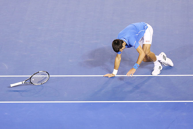 Novak Djokovic drops his racquet as he falls during his Australian Open men's final against Andy Murray on Sunday