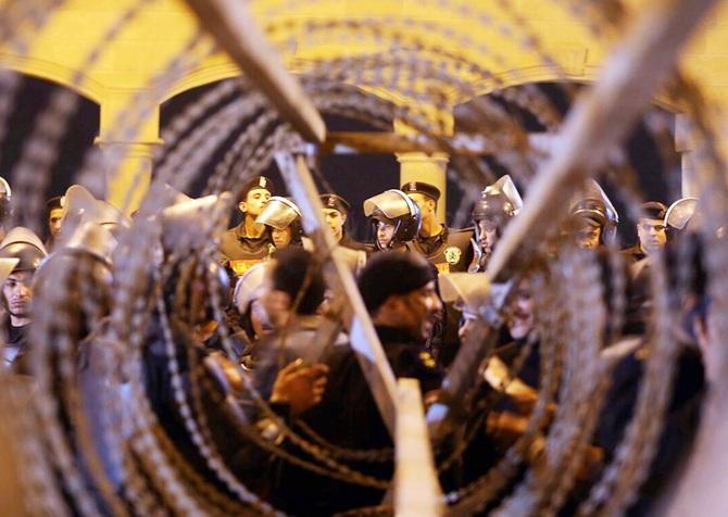 Policemen and soccer fans are seen through barbed wire as fans attempt to enter a stadium 