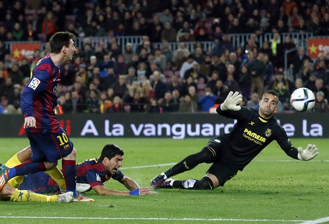 Barcelona's Lionel Messi, left, kicks the ball next to teammate Luis Suarez