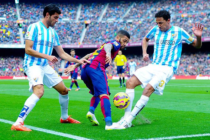 Dani Alves of FC Barcelona fights off a challenge by Welligton Robson (right) and Miguel Torres of Malaga CF during their La Liga match at Camp Nou in Barcelona, on Saturday