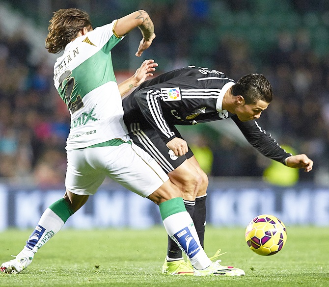 Cristiano Ronaldo, right, of Real Madrid is tackled by Damian Suarez of Elche