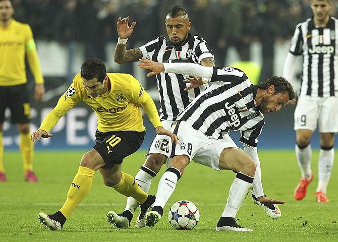 Henrikh Mkhitaryan (left) of Borussia Dortmund competes for the ball with Arturo Vidal (centre) and Claudio Marchisio of Juventus FC