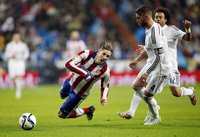 Atletico Madrid's Fernando Torres (left) is fouled by Real Madrid's Sergio Ramos