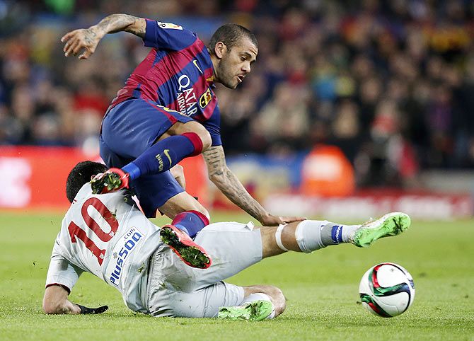 Barcelona's Daniel Alves is tackled by Atletico Madrid's Arda Turan 