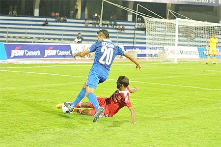 Bengaluru's Keegan is challenged by a Pune FC player during their I-League match at the Sree Kanteerava Stadium in Bengaluru on Saturday