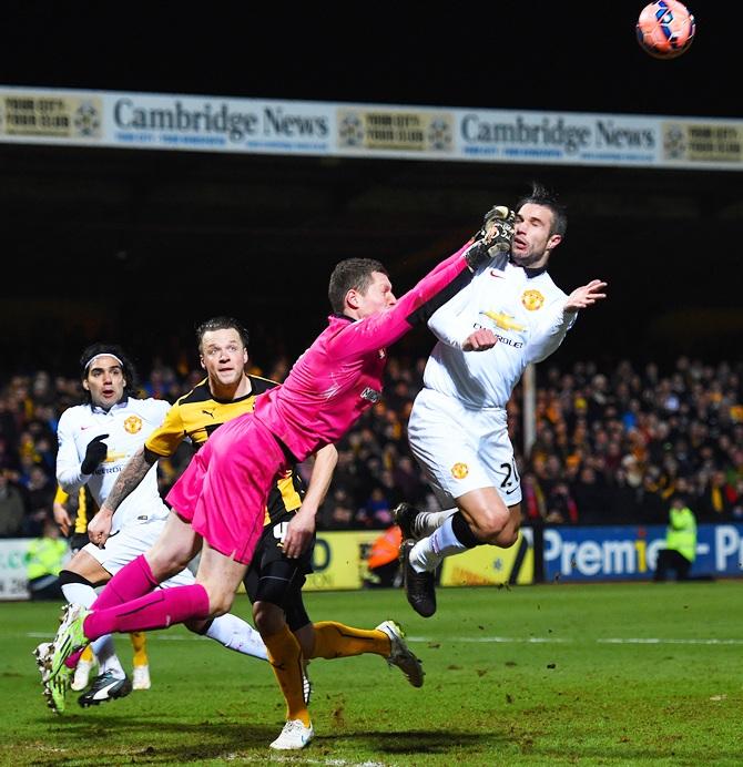 Chris Dunn of Cambridge United makes contact with Robin van Persie of Manchester United