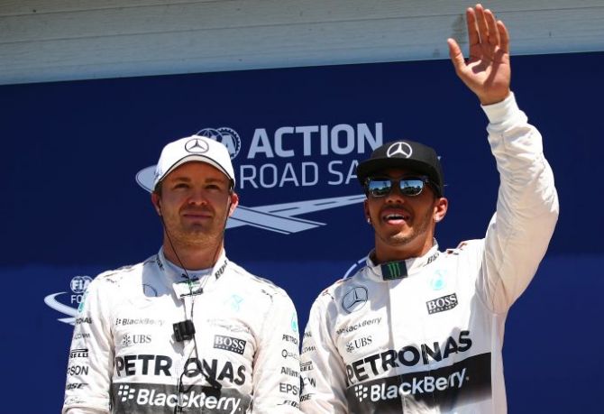 Lewis Hamilton of Great Britain and Mercedes GP celebrates after securing poles position whilst second placed Nico Rosberg of Germany and Mercedes GP looks on