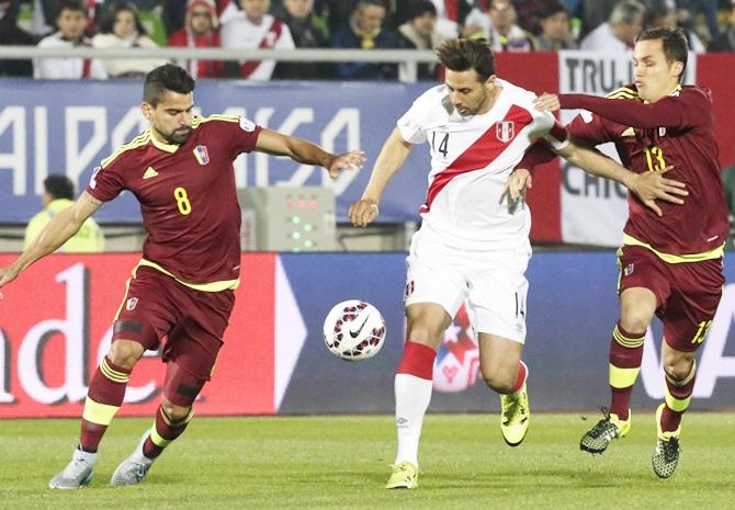 Venezuela's Tomas Rincon, left, and Luis Seijas challenge Peru's Claudio Pizarro